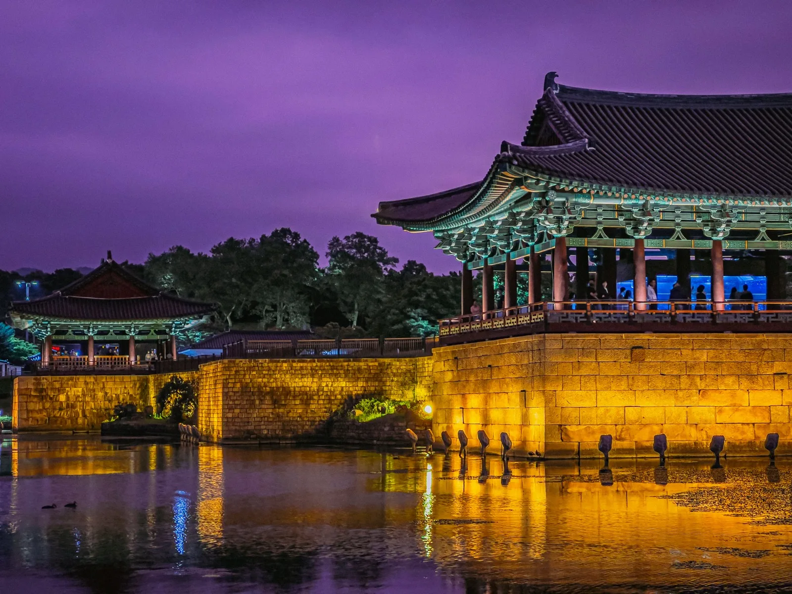 Illuminated pavilions and stone walls at Anapji reflected in still water under a purple night sky