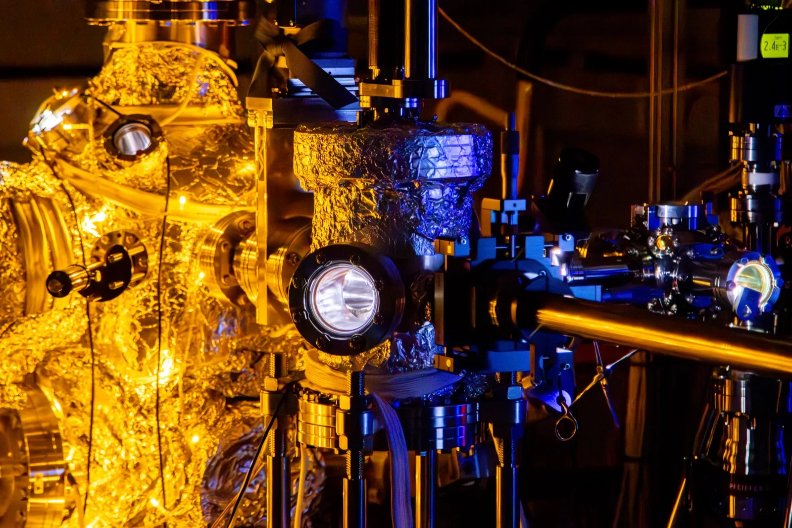 An ARPES instrument wrapped in warm holiday lights with metallic chambers and optics glowing in the dark